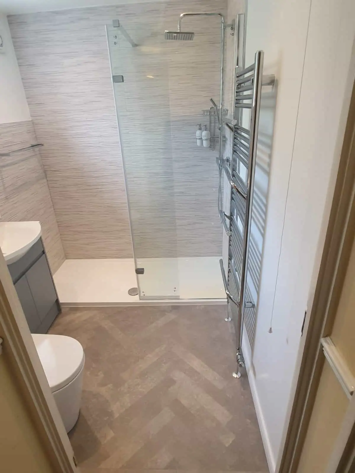 Modern bathroom with a glass shower enclosure, chrome towel rail and tiled walls