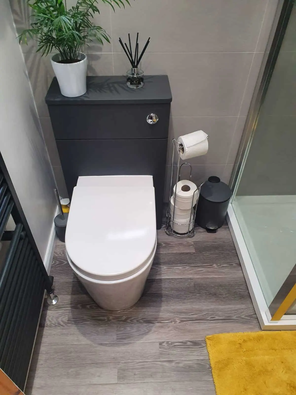 Modern bathroom with a white toilet, dark vanity unit and wood-effect flooring