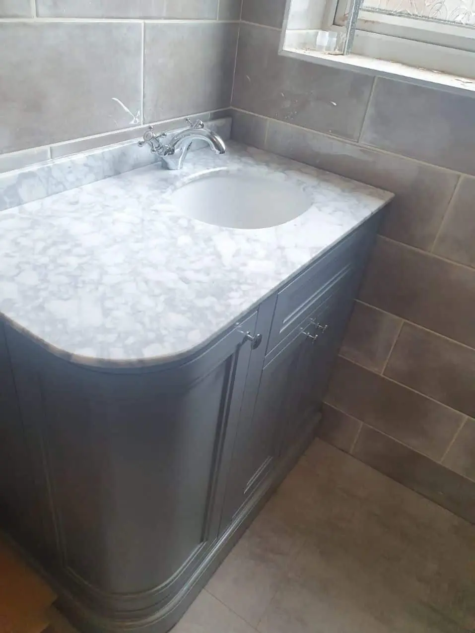 Grey bathroom vanity with a marble-effect countertop and inset basin