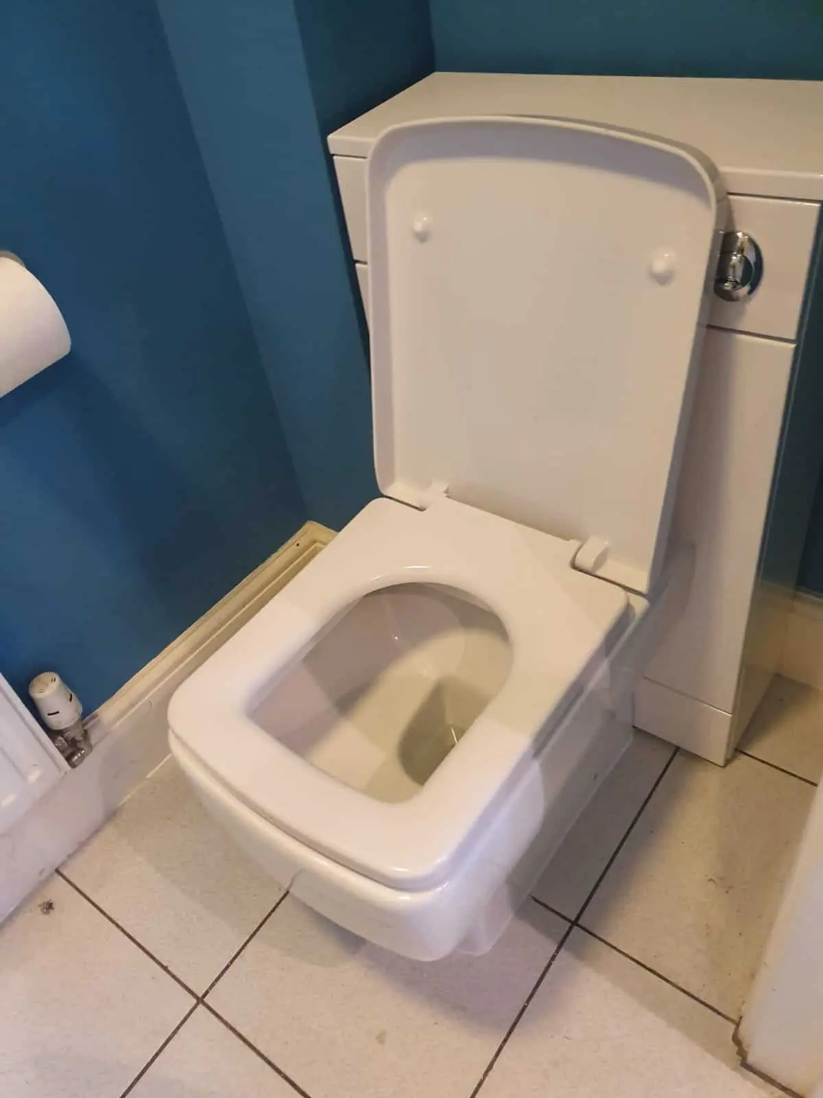 White toilet fitted in front of a vanity unit, with the pipework concealed.