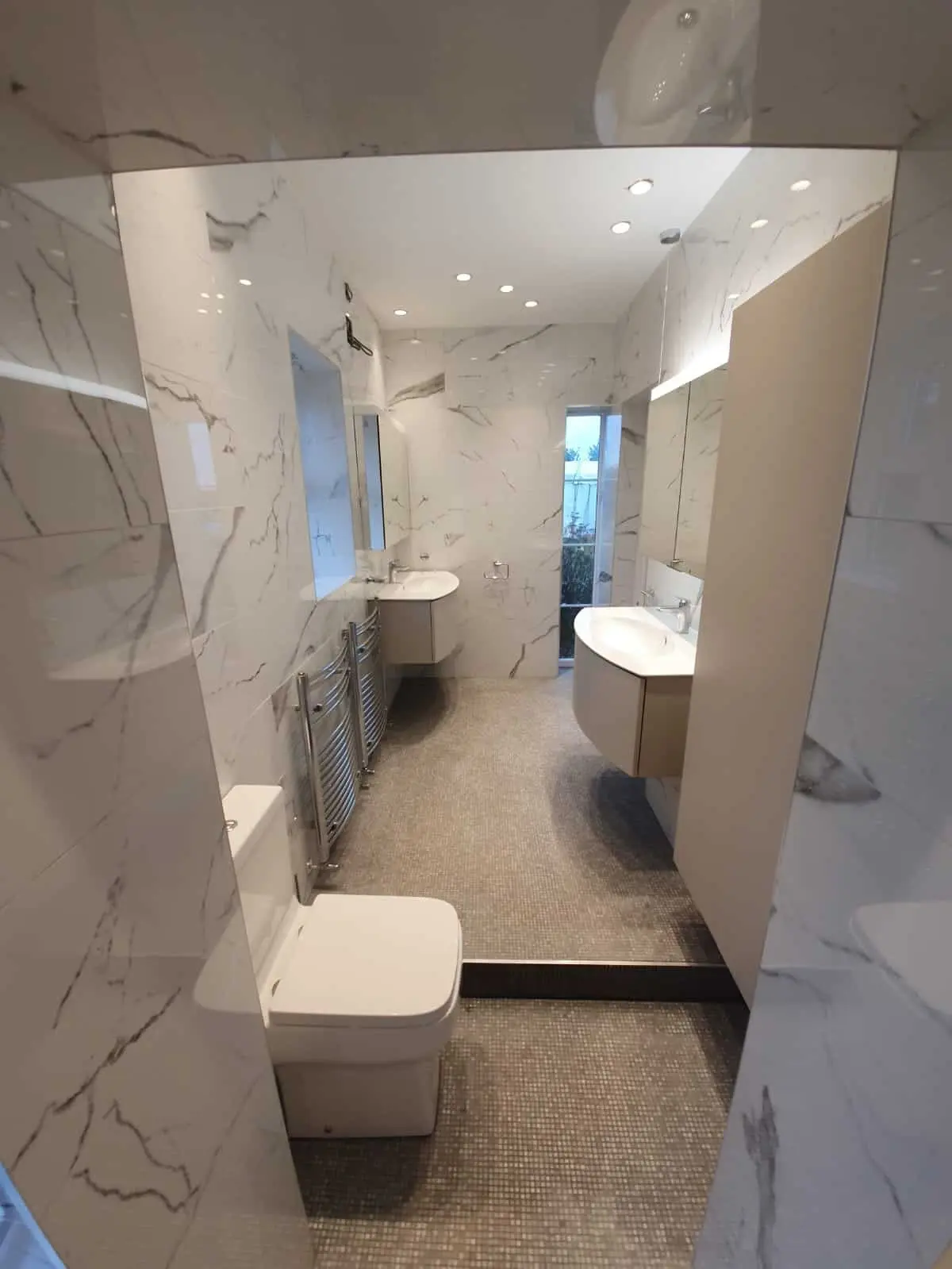 Modern bathroom with marble-effect walls, wall-hung basins and a toilet