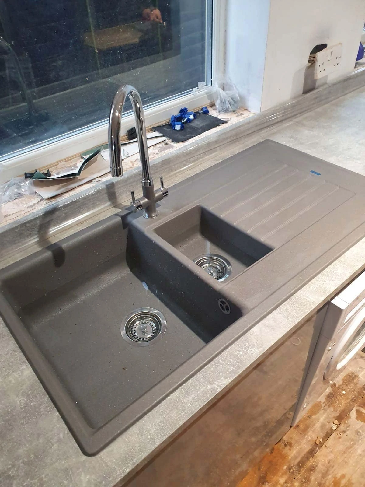 Dark grey double-bowl kitchen sink with a right-hand drainer and chrome mixer tap.