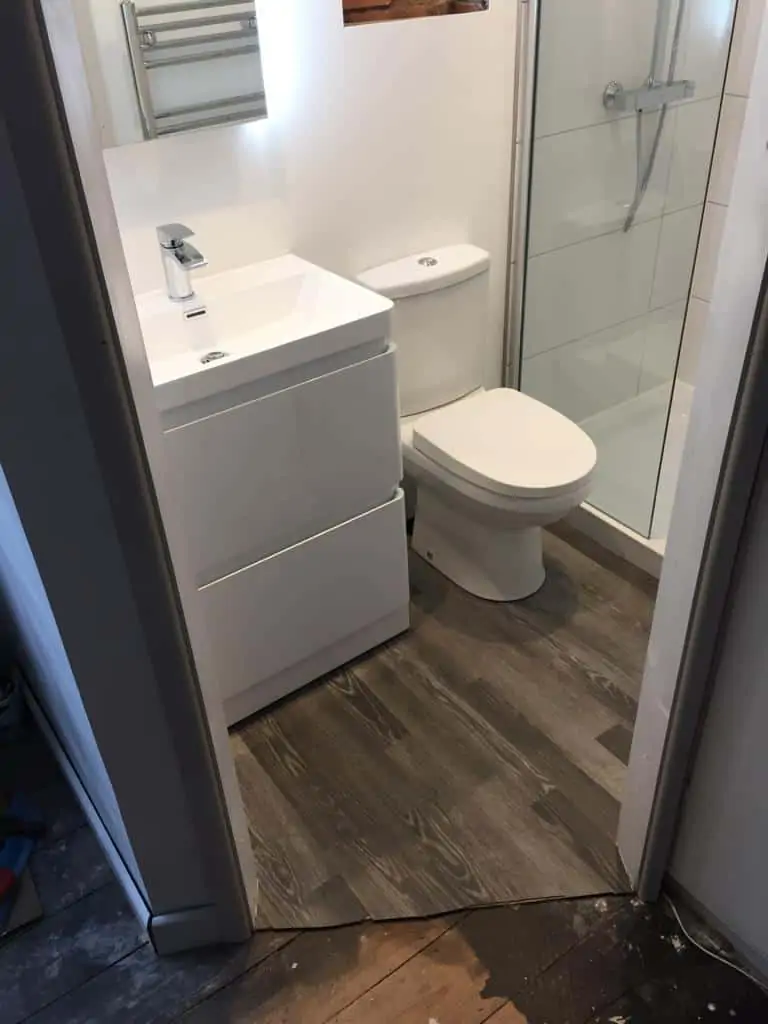 Compact ensuite bathroom with a grey vanity unit, toilet and glass shower enclosure
