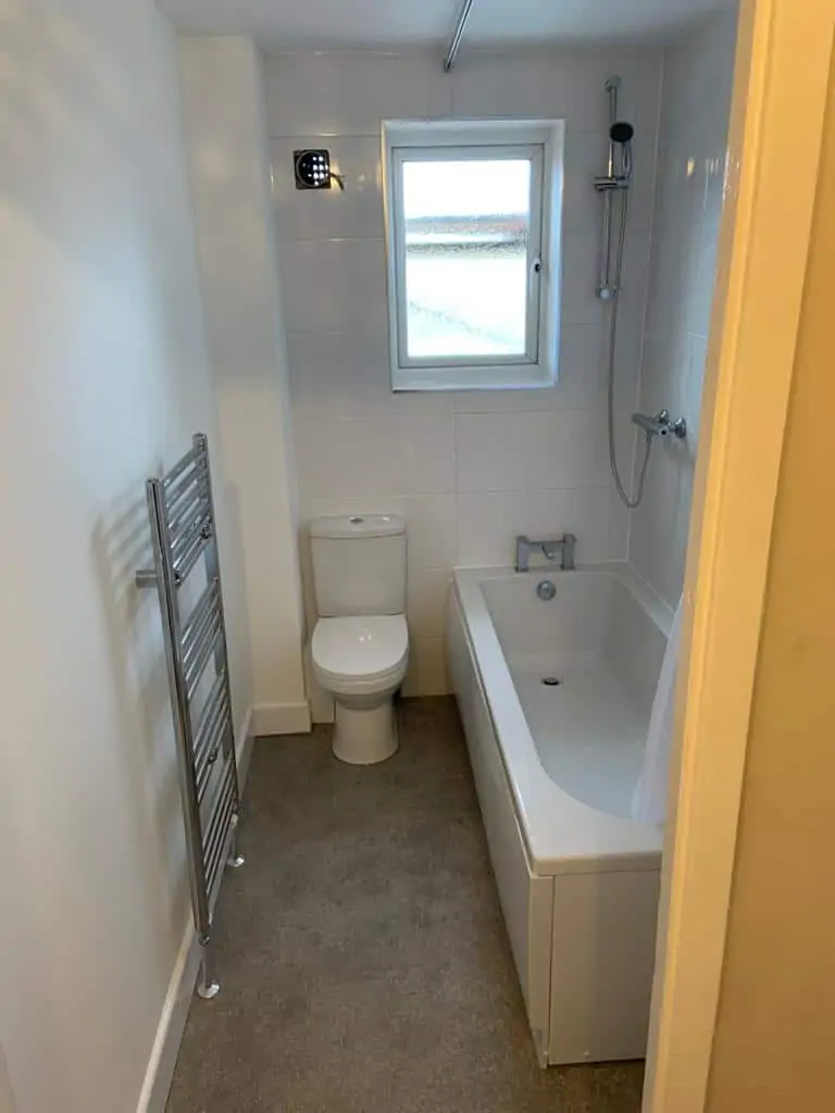 Refitted bathroom with a bath and shower, toilet and chrome towel radiator