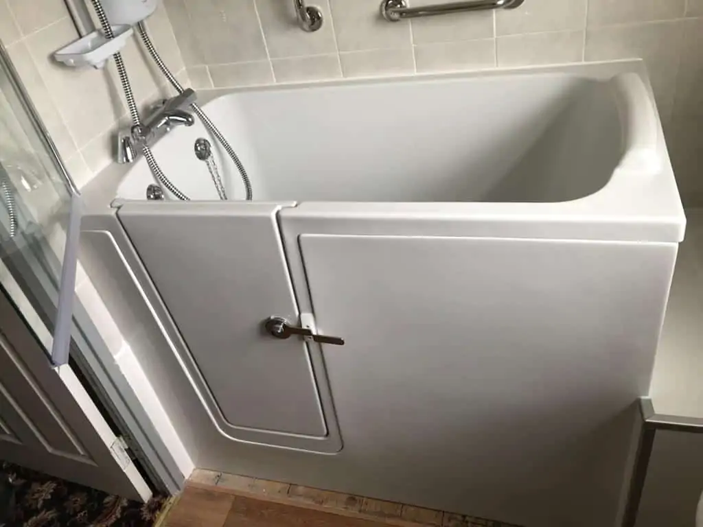 White walk-in bath with an inward-opening door, shower fittings and grab rail