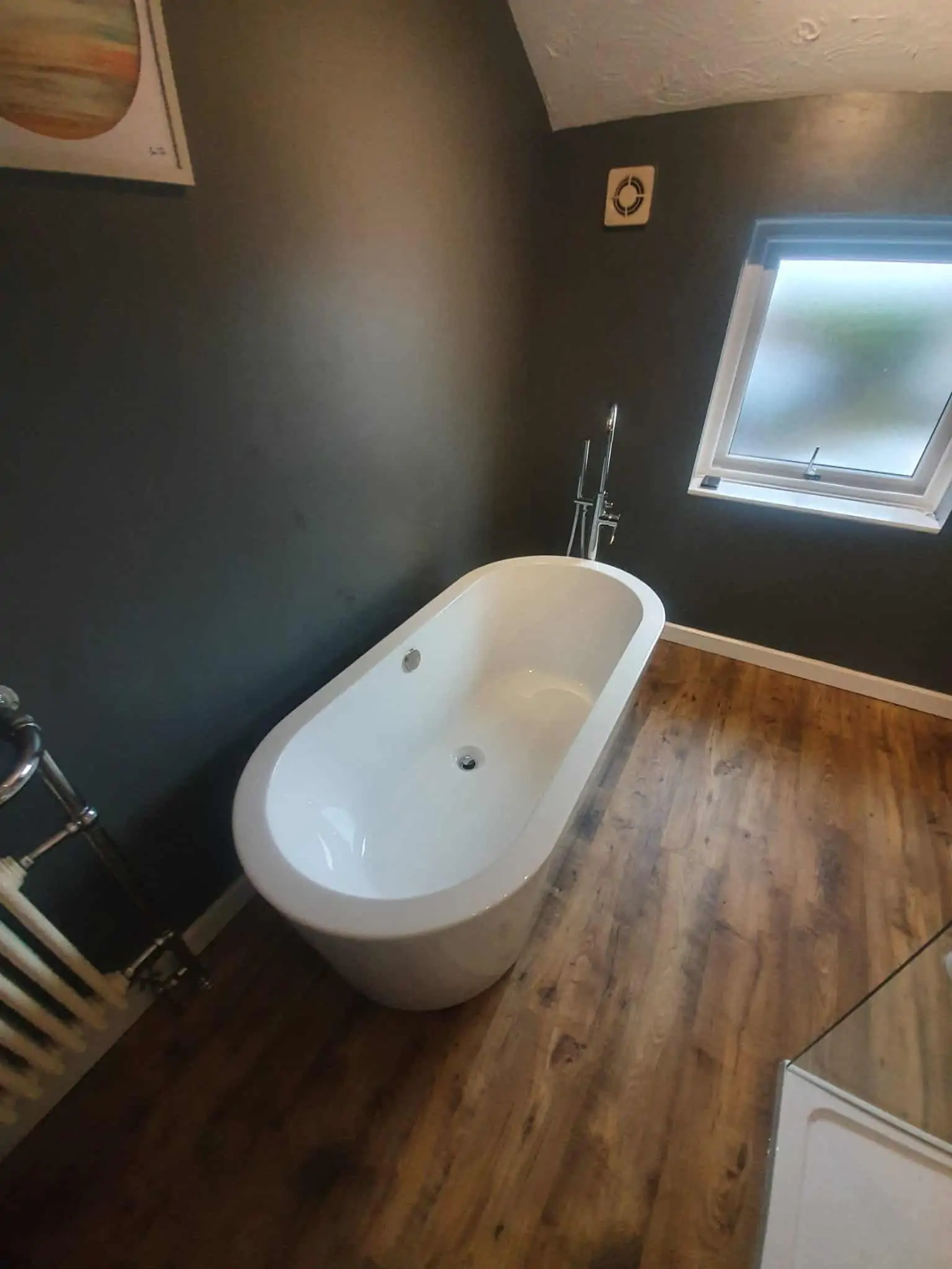 White freestanding bath beside a frosted window in a modern bathroom
