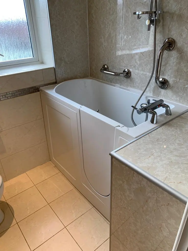 Walk-in bath with an access door, grab rails and a shower attachment