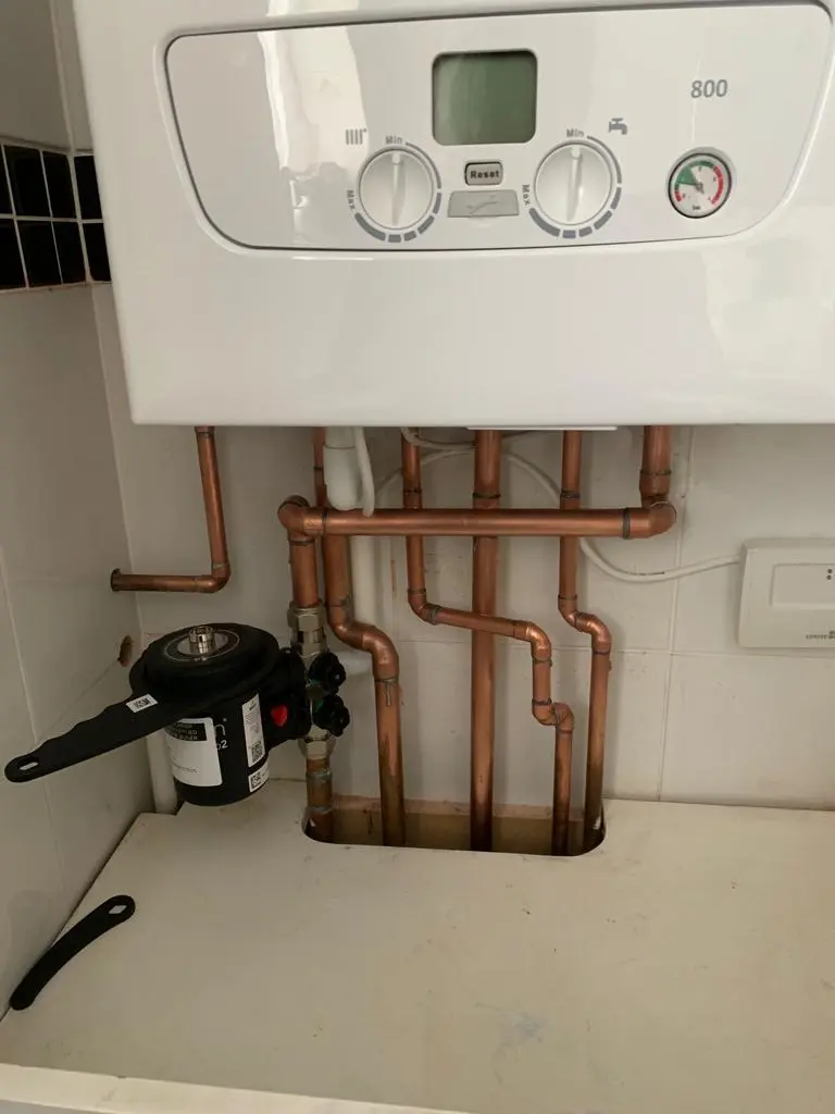 White wall-mounted boiler above neatly routed copper pipework