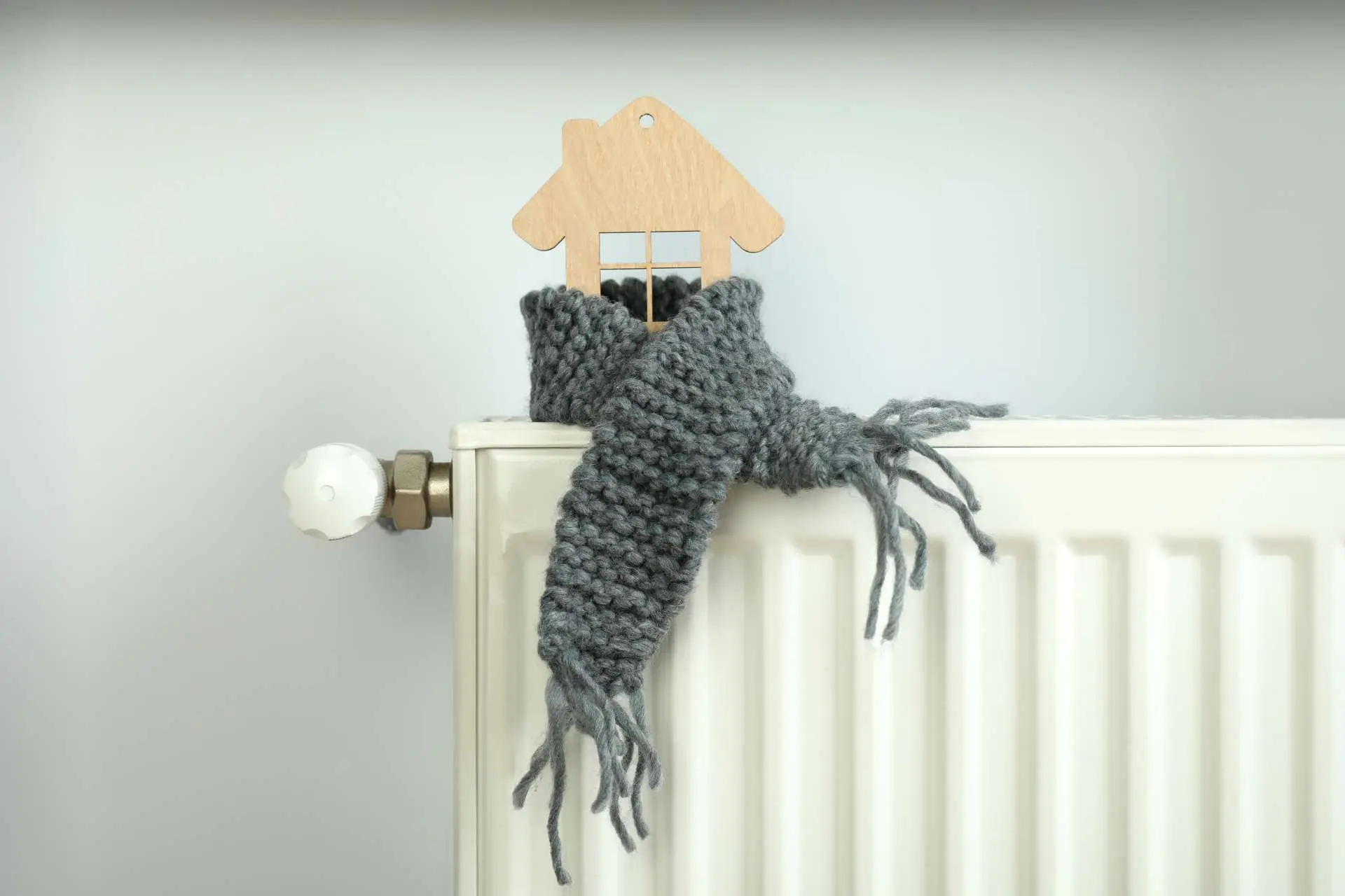 White radiator with a grey knitted scarf draped over it