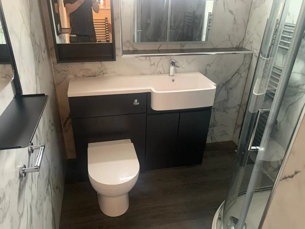 Renovated bathroom with a wall-hung vanity, toilet and glass shower enclosure