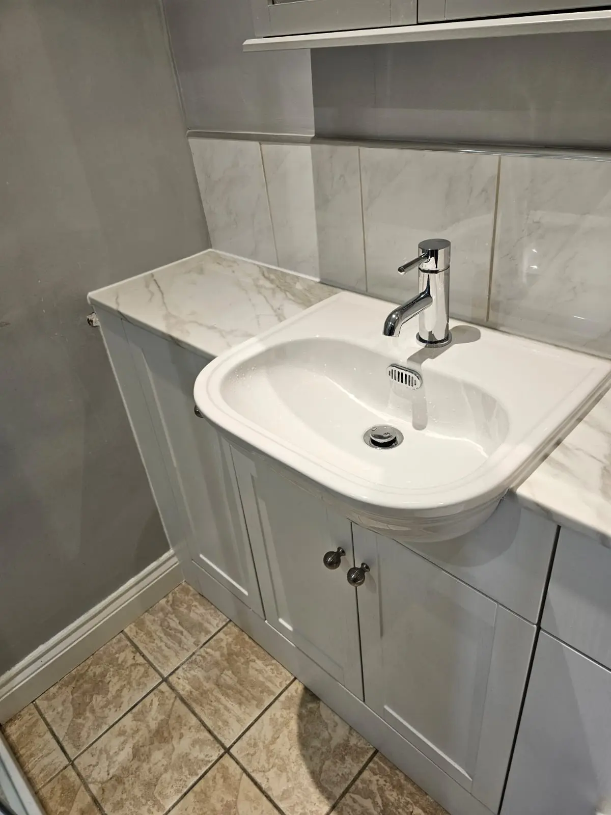 White integrated bathroom vanity with a marble-effect worktop, basin and chrome tap