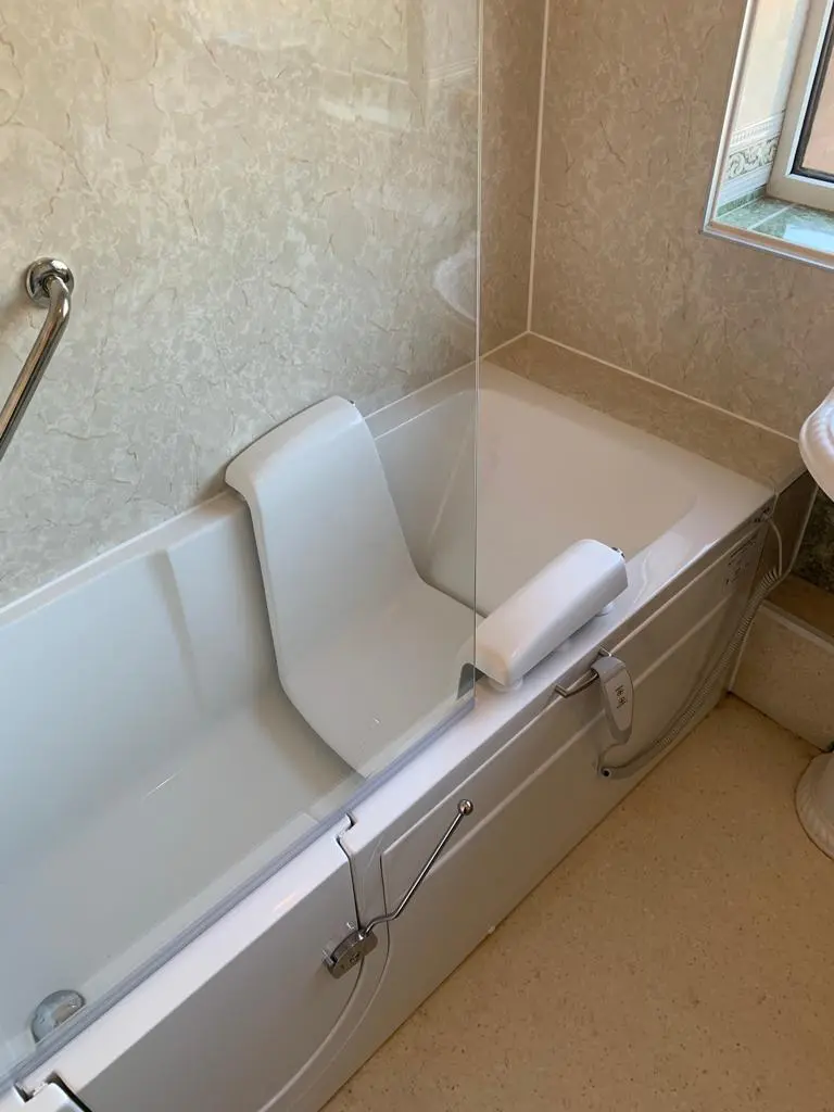 White walk-in bath with an inward-opening door, built-in seat and glass shower screen